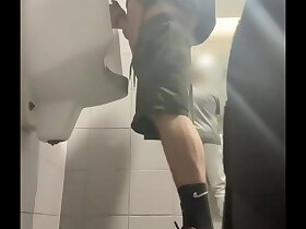 2 boys in sneakers having fun at public toilets' urinal