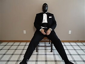 Seated in a tuxedo wearing a rubber cock and ball sheath and playing with my cock until I cum.